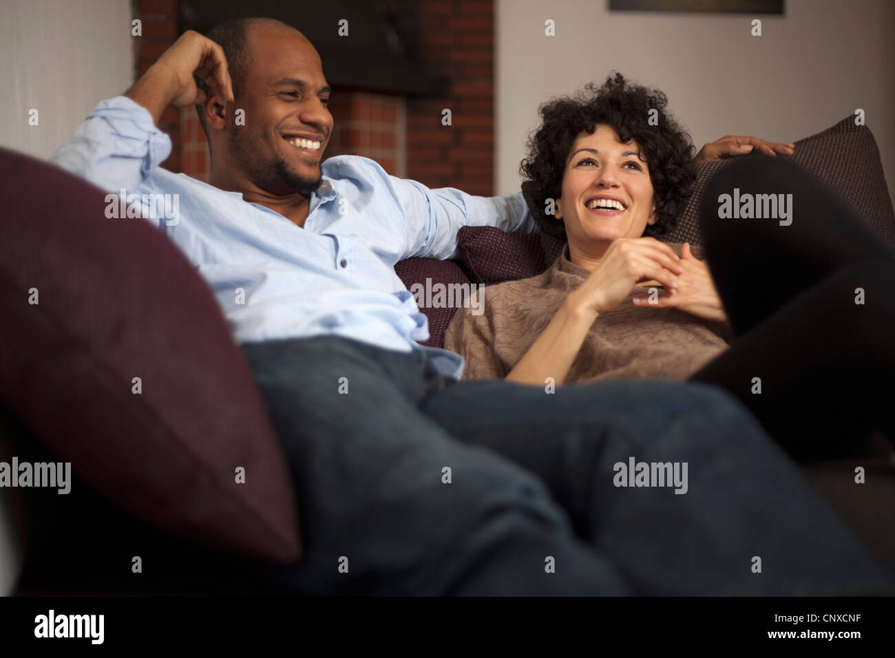 Una ridente giovane rilassante insieme su un divano Foto Stock