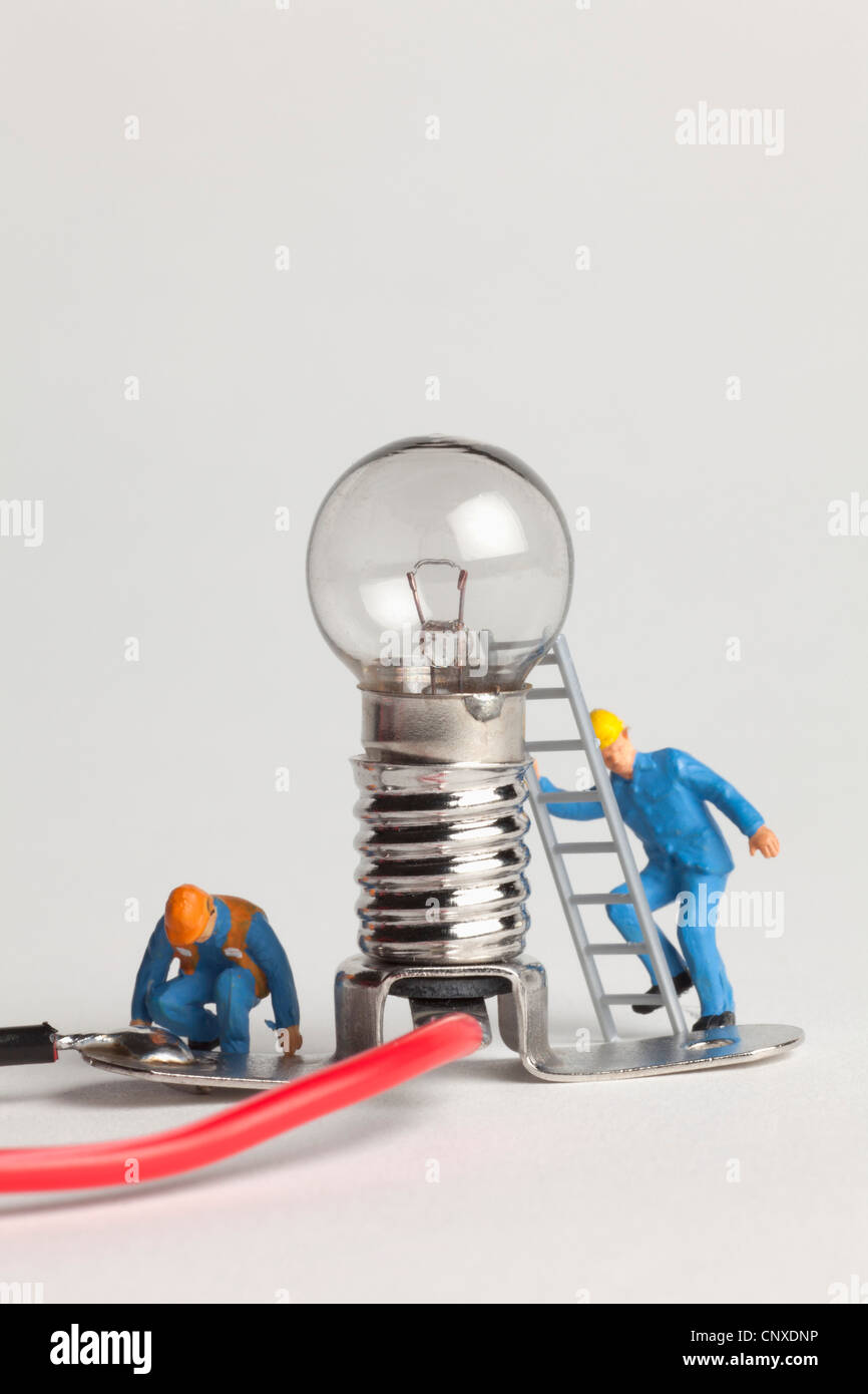 Elettricista in miniatura figurine lavorando su una lampadina Foto Stock