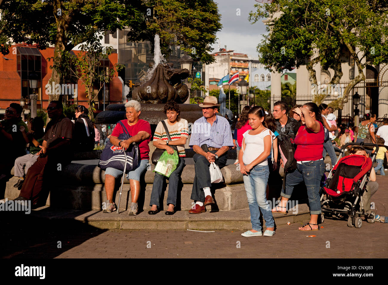 La gente del posto seduto su una fontana su Central Park Parque Central nella capitale San Jose, Costa Rica, America Centrale Foto Stock