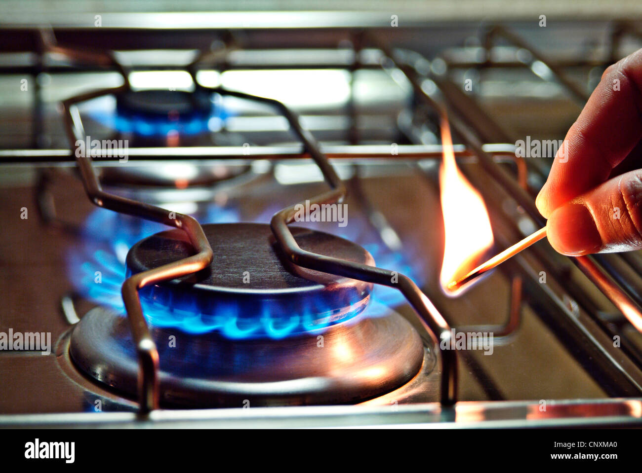 Close up di un bruciatore di un fornello a gas che è accesa con un fiammifero. Foto Stock