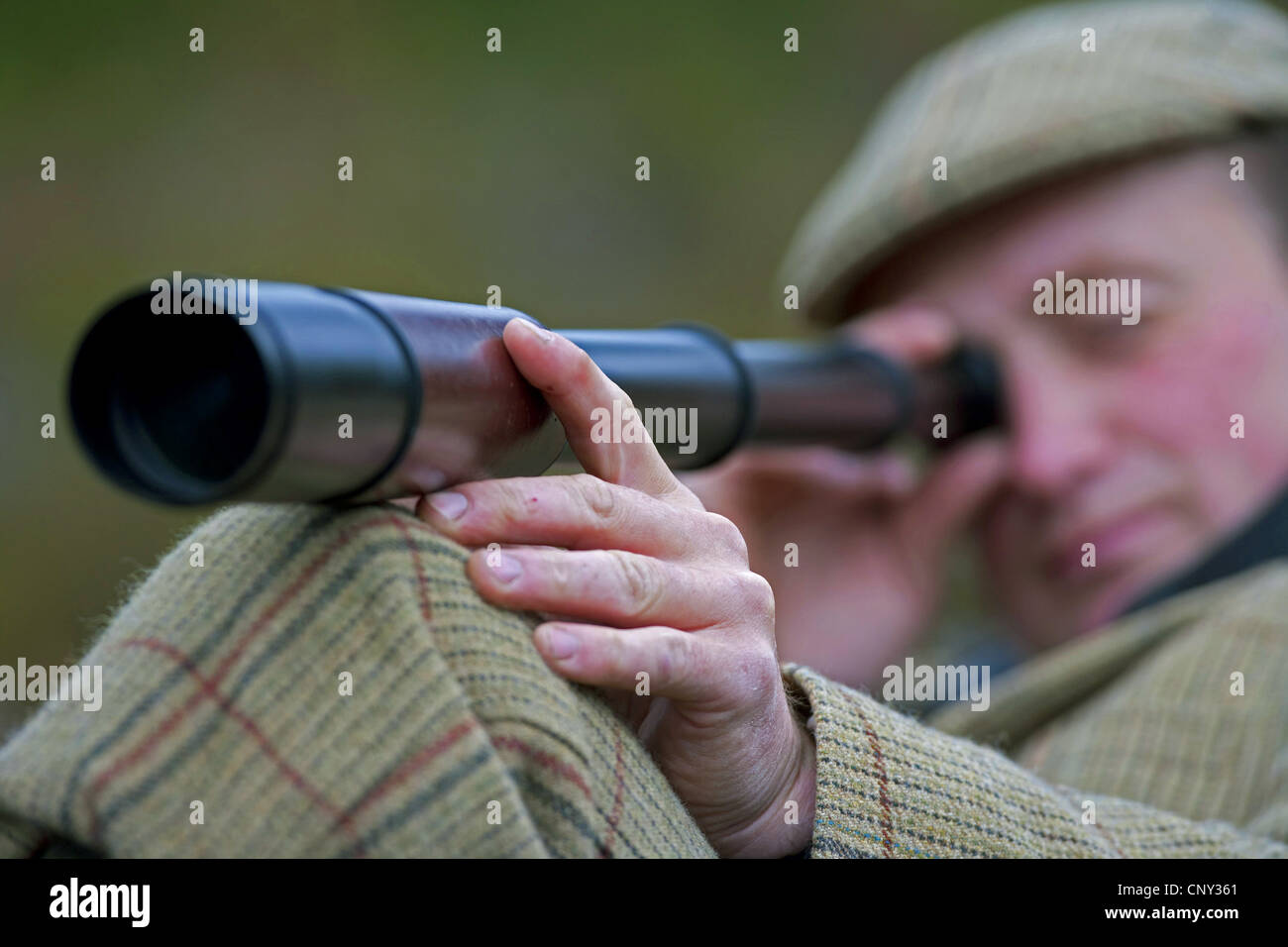 Deer stalker a caccia di cervi reed osservando con un telescopio, Regno Unito, Scozia, Cairngorms National Park Foto Stock