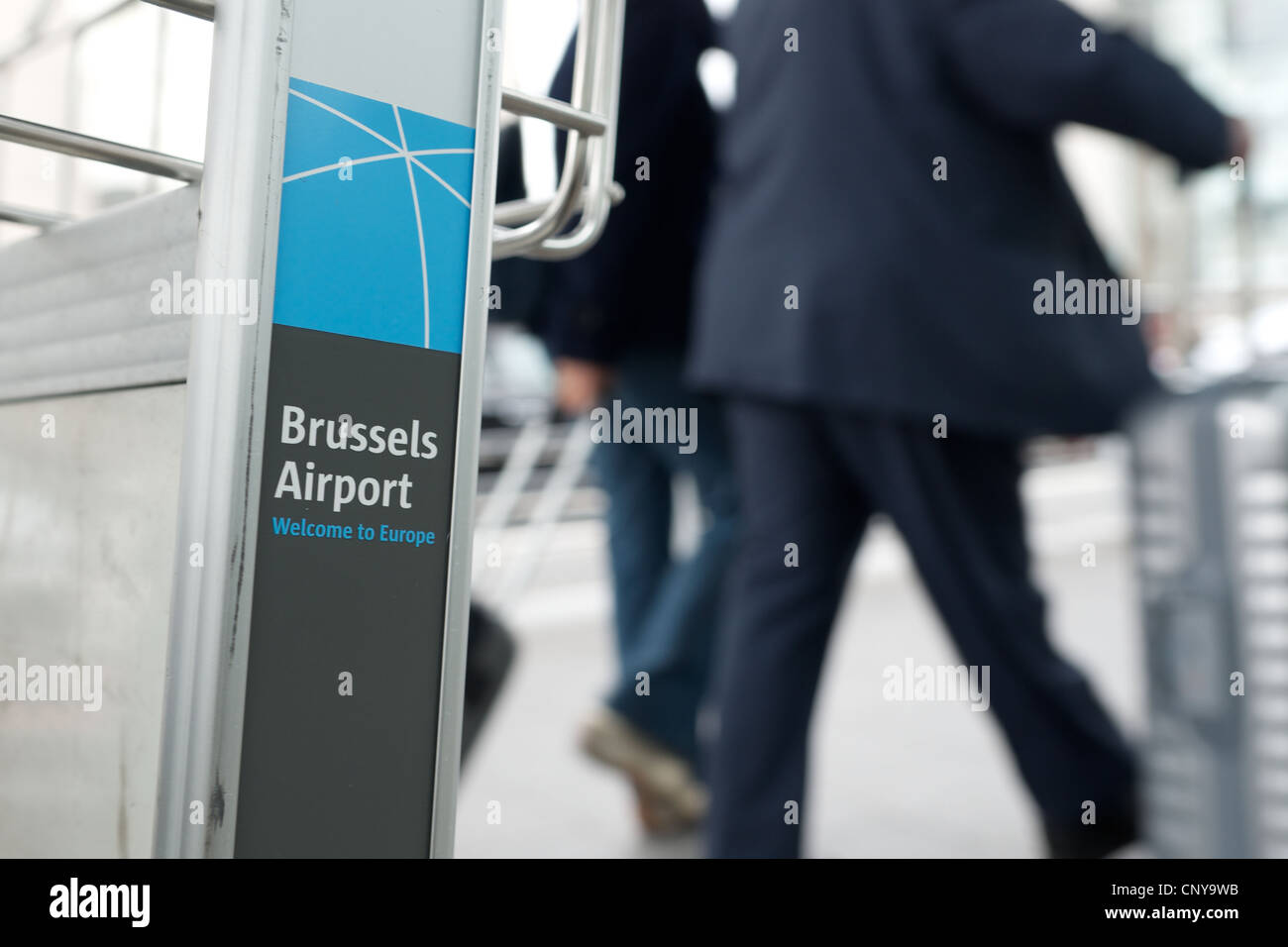 L'aeroporto di Bruxelles. Logo sul bagaglio con trolley fuori fuoco i passeggeri in viaggio d'affari in background Foto Stock