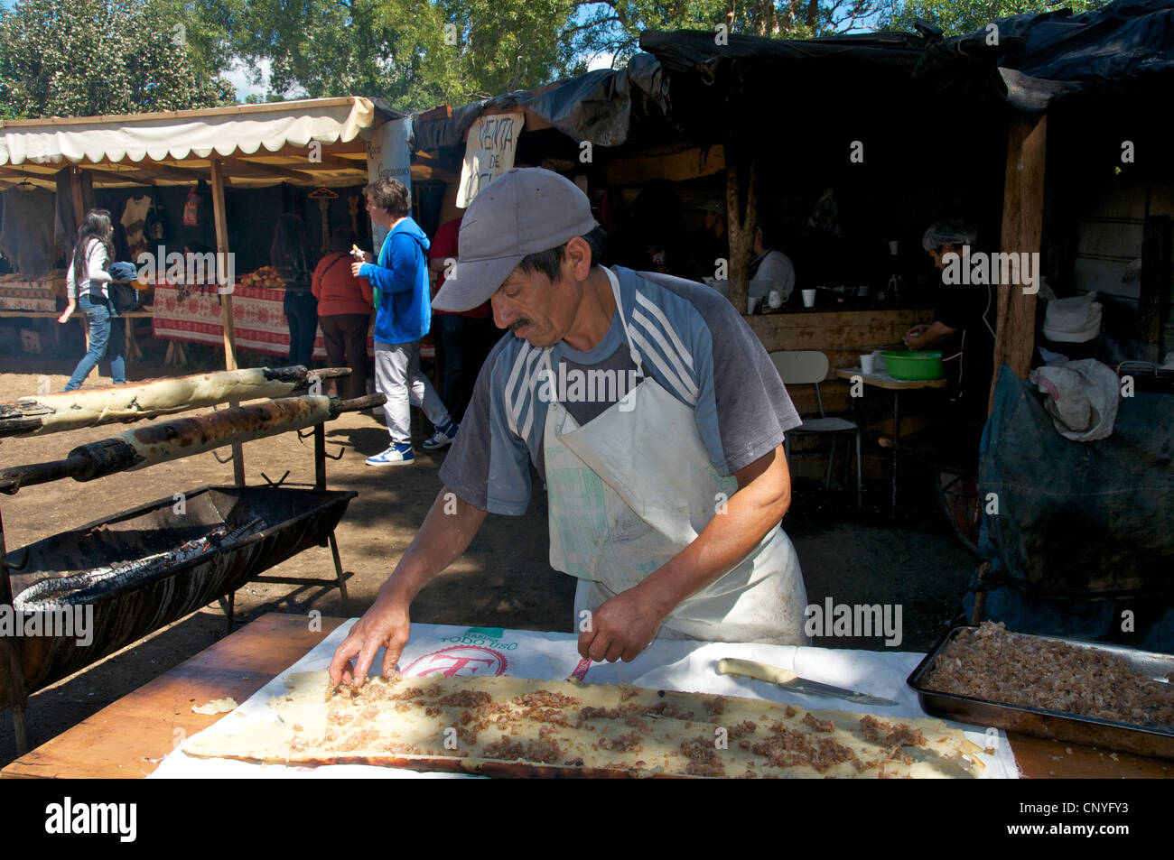 L'uomo la preparazione di carne ripieno su pane piatto Curaco de Velez Chiloe Cile Foto Stock