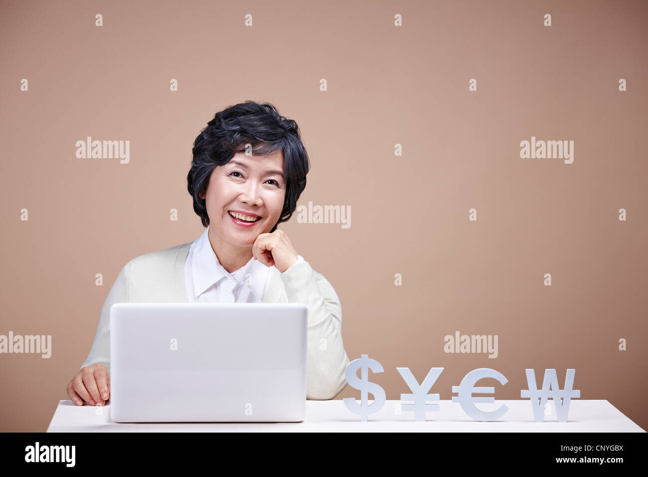 Una donna anziana con valuta estera e il computer portatile Foto Stock