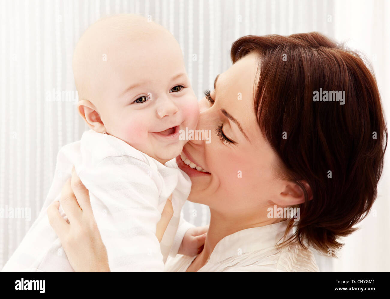 Felice giovane madre tenendo un bambino gioca a ridere divertendosi, sano concetto di famiglia Foto Stock