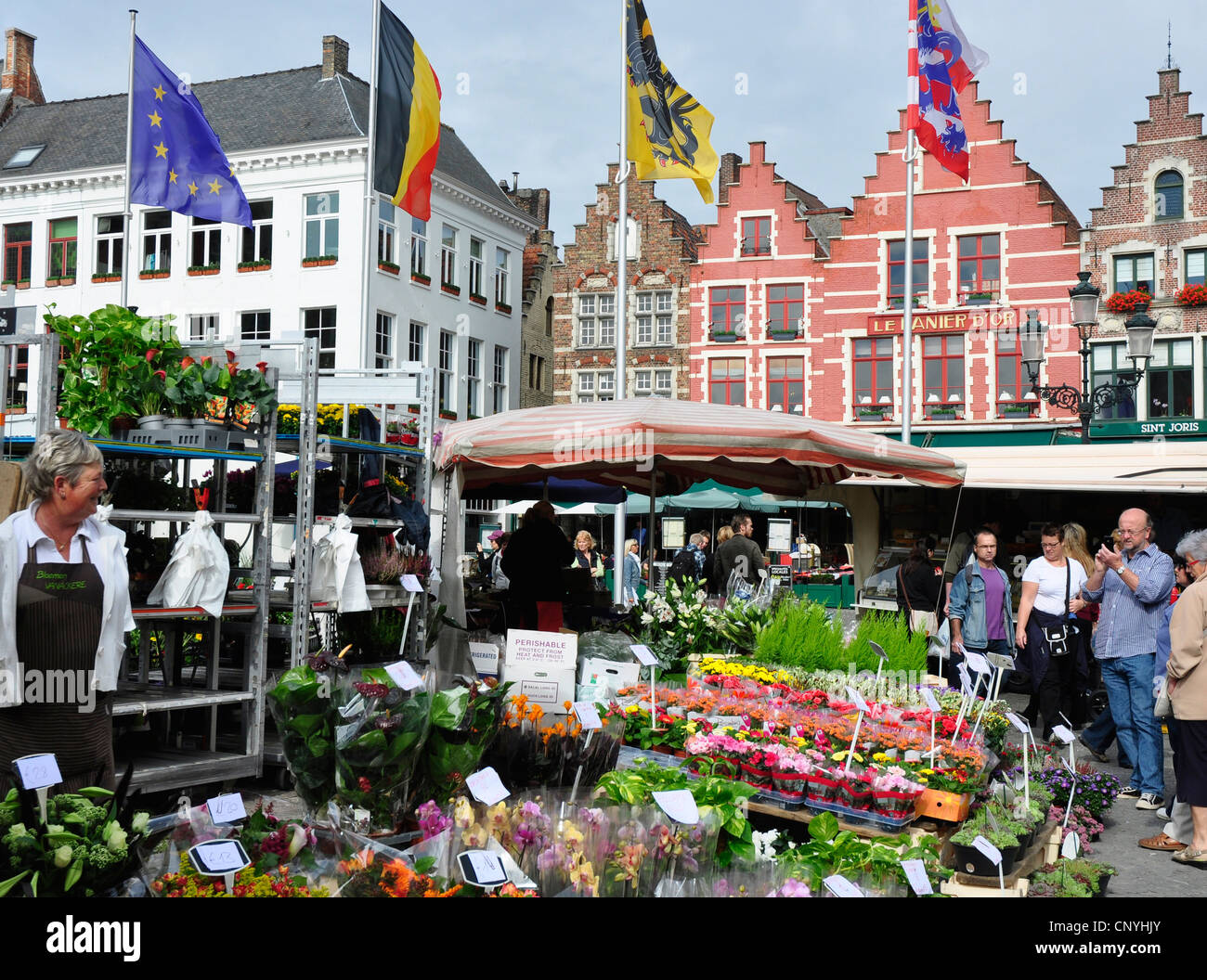 Belgio - Bruges - Piazza del Mercato - fiori colorati e bancarelle di frutta e verdura - luce del sole - Blu cielo Foto Stock