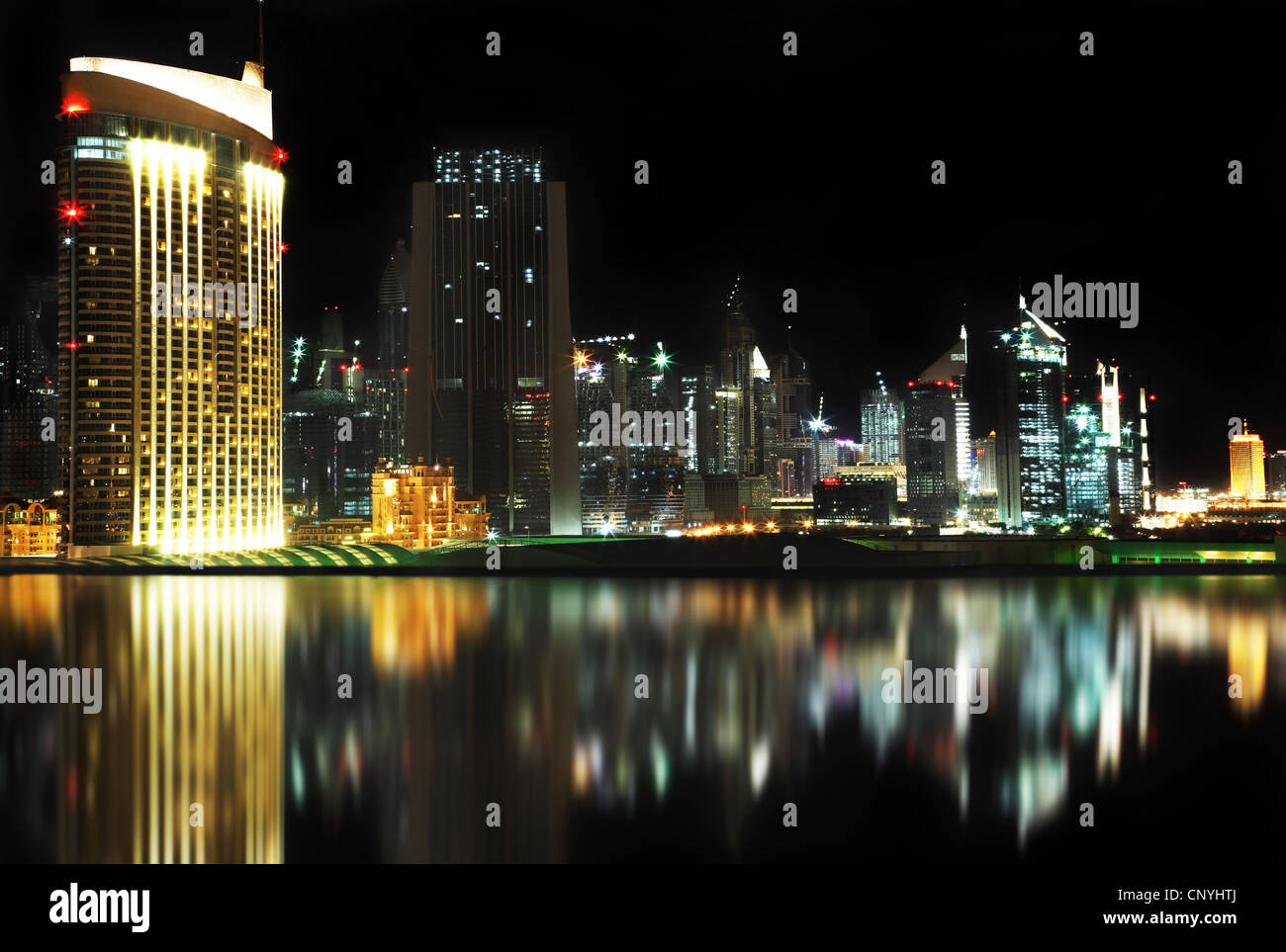 Dubai centro di notte riflessa nell'acqua Foto Stock