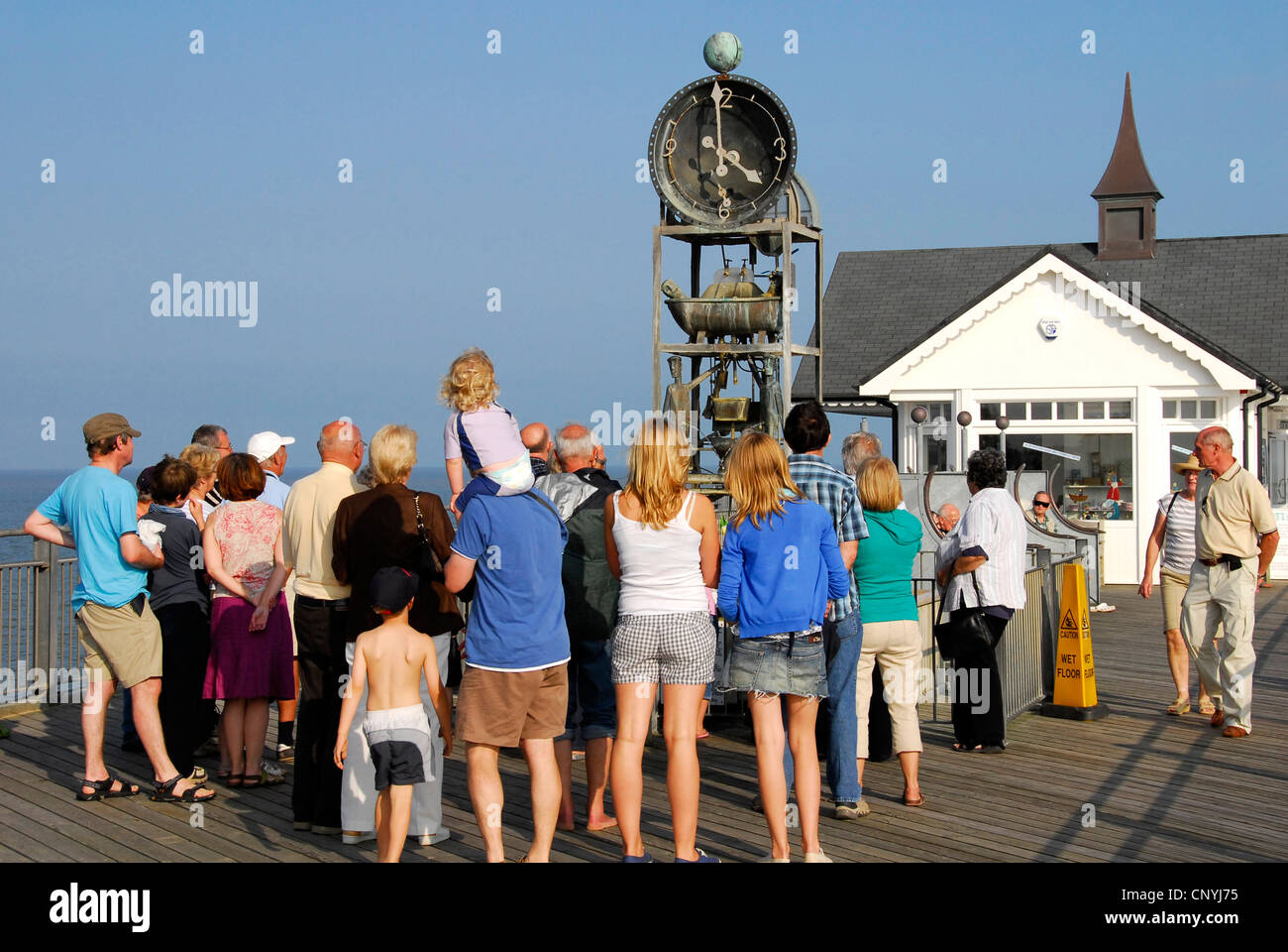 Suffolk - Southwold pier - estate folla in attesa di vedere il comico orologio ad acqua eseguire sull'ora - la luce del sole blu cielo Foto Stock
