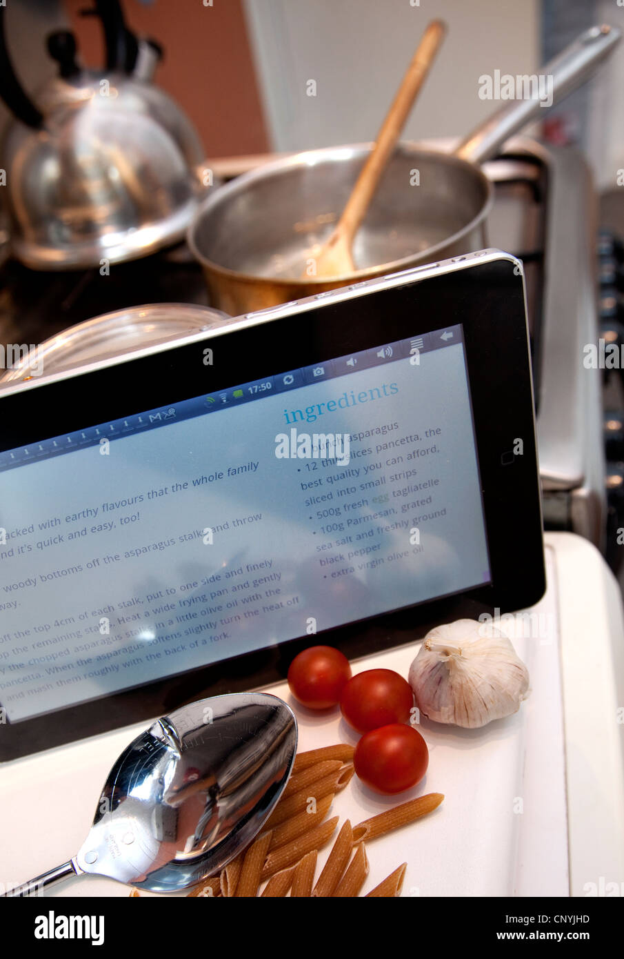 La cottura da una ricetta su internet su un dispositivo tablet, Londra Foto Stock