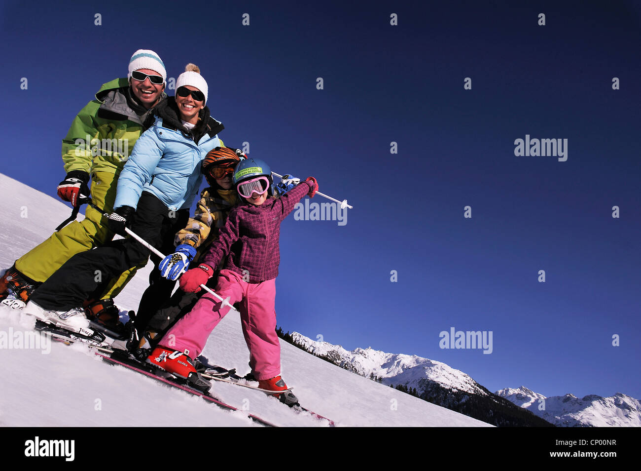 Famiglia con due figli su sci felicemente in piedi uno dopo l'altro in un snowbound pendio di montagna, Francia Foto Stock
