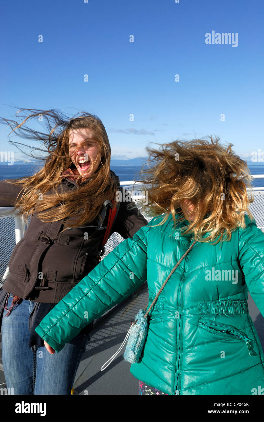 Due femmine con i loro capelli essere soffiata dal vento durante una traversata in traghetto. Foto Stock
