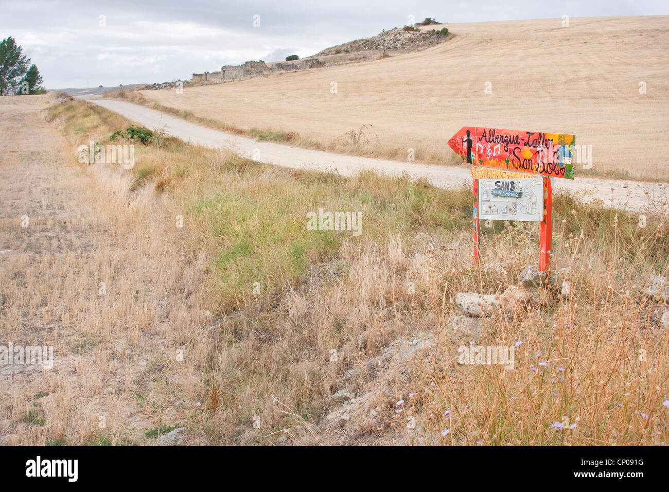 Segno di direzione presso il Cammino di Santiago attraverso essiccato fino prato e paesaggio di campo che mostra il modo di pellegrino la ostello a San Bol, Spagna, Kastilien und Len, San Bol Foto Stock