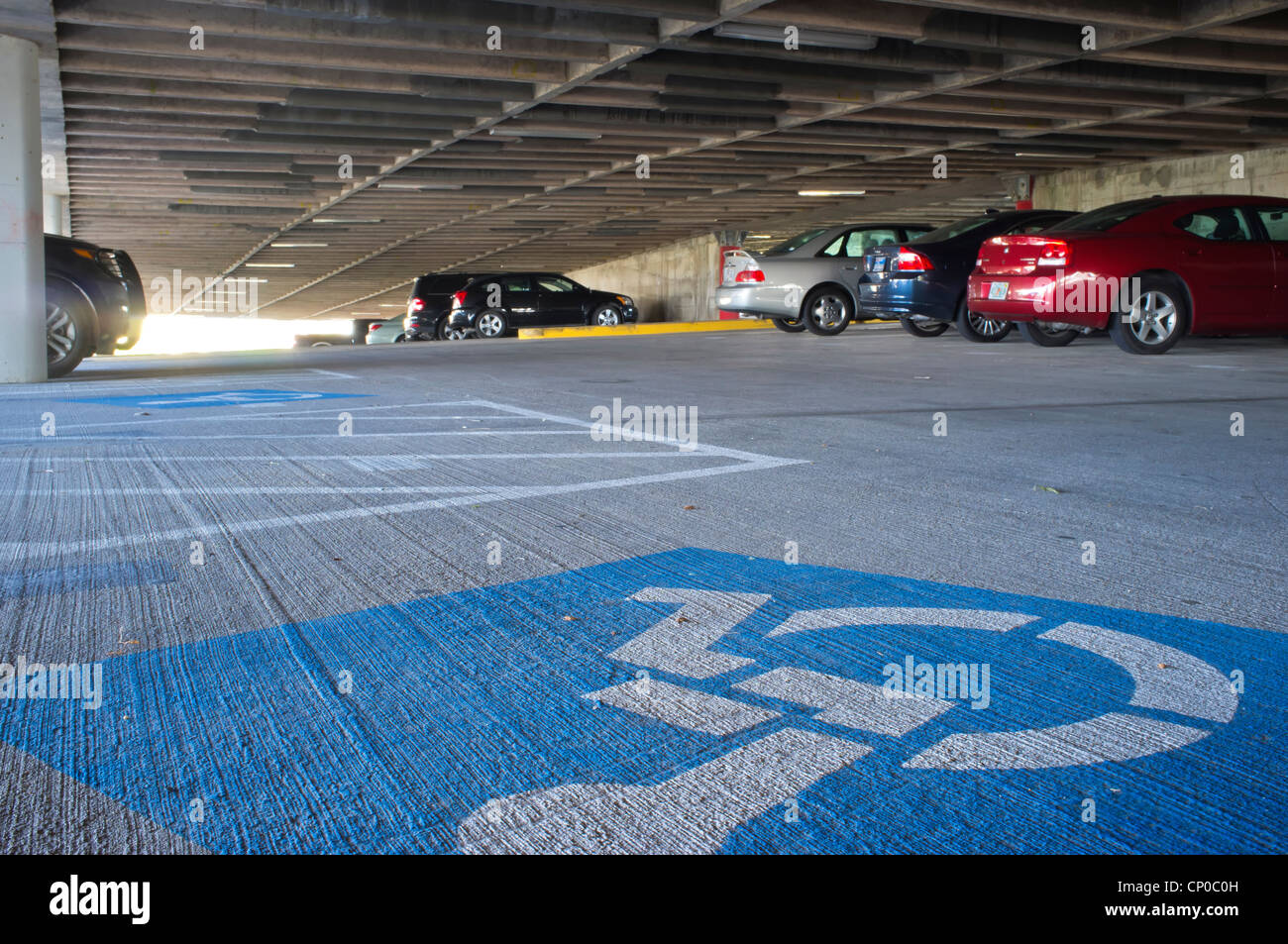 Parcheggio Disabili spazio contrassegnato con sedia a rotelle su sfondo blu in un garage pubblico Foto Stock