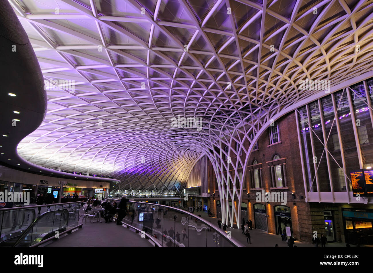 Night Time Kings Cross Railway Station, atrio di partenza con piano rialzato e futuristica struttura del tetto illuminata a motivi geometrici, Londra Inghilterra UK Foto Stock