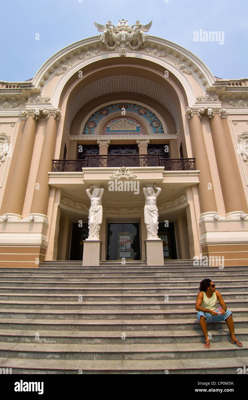 In orizzontale ampia angolazione di un uomo seduto di fronte al Saigon Opera House, Nhà hát lớn Thành phố Hồ Chí Minh in Ho Chi Minh City. Foto Stock