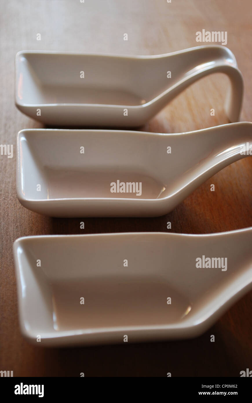 Tre vuoto bianco di ceramica di contenitori per alimenti in legno naturale sfondo tabella Foto Stock