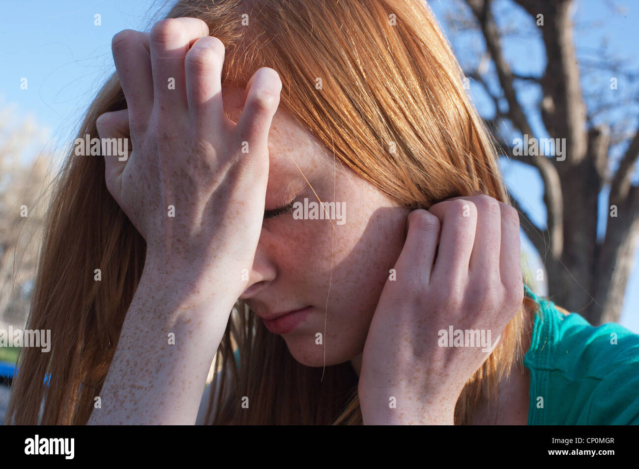 In prossimità di un sedicenne ragazza ansia e che copre il volto con le mani all'esterno. Foto Stock