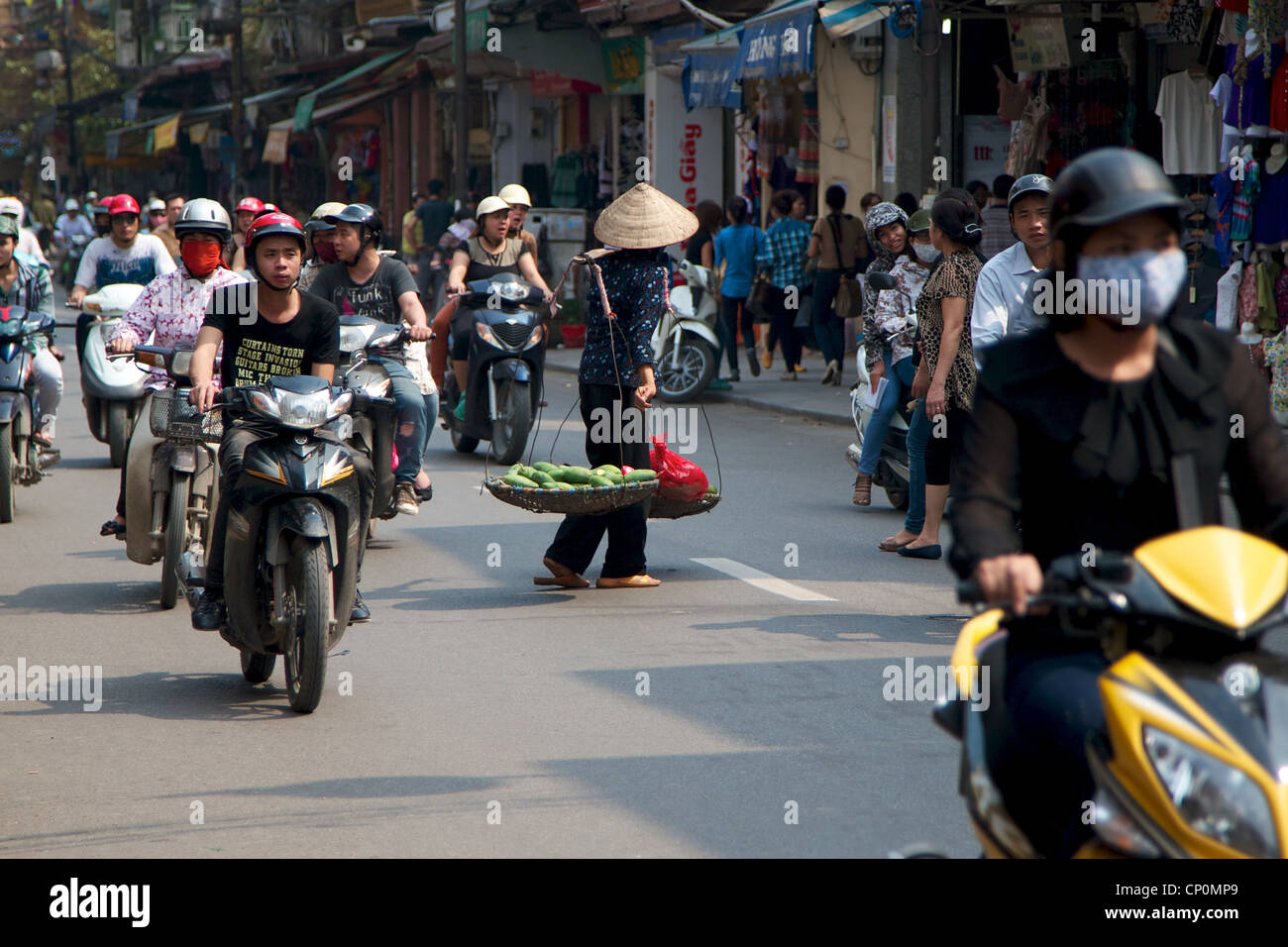 Un cibo di strada venditore attraversando la strada trafficata in Hanoi, Vietnam. Foto Stock