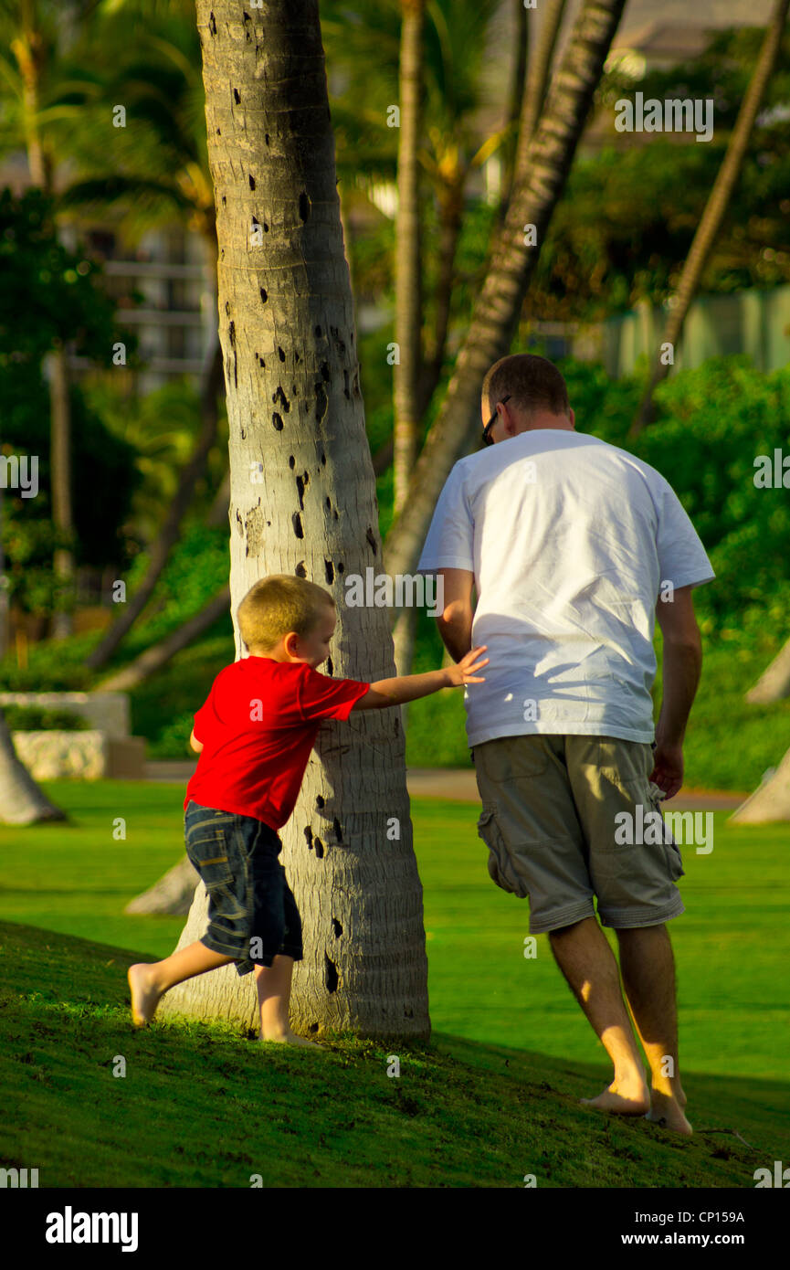 Quattro anni ragazzo autistico insegue il padre intorno palme. Foto Stock