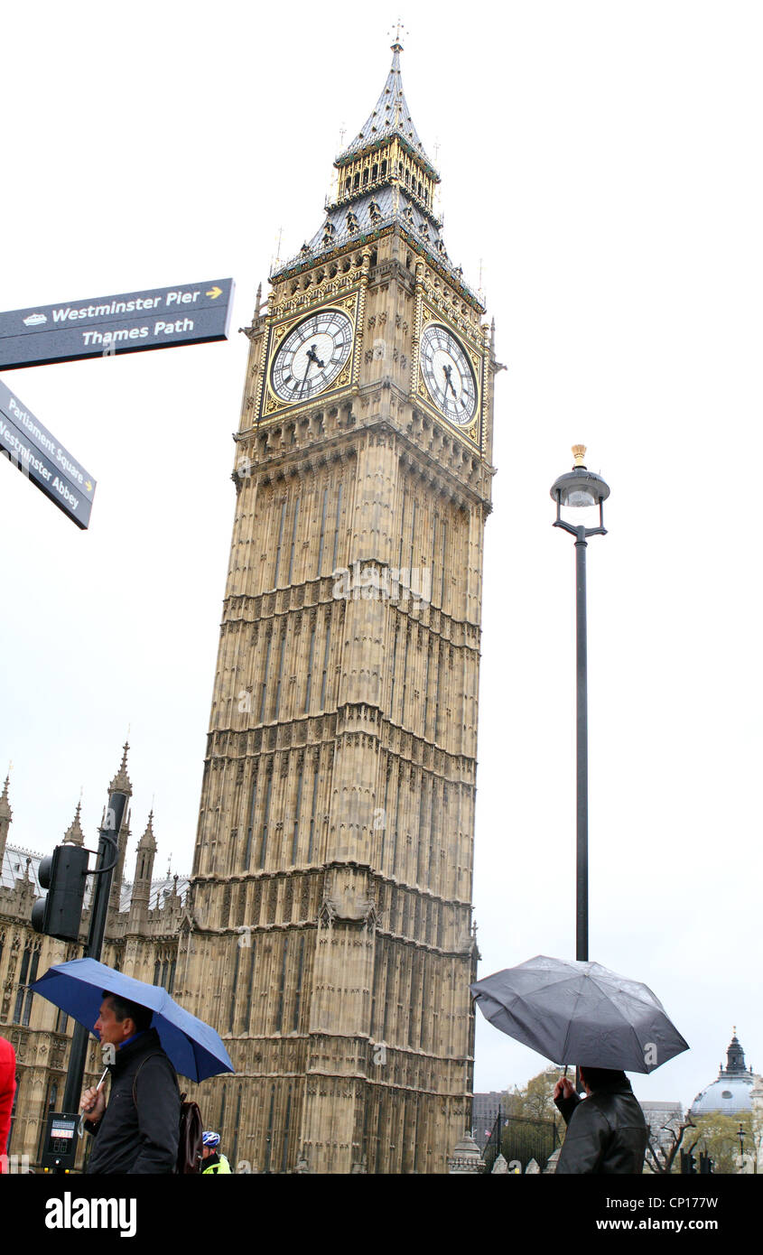 Persone con ombrelloni fino a piedi passato il Big Ben a Londra Foto Stock