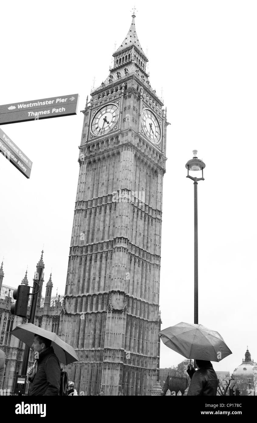 Persone con ombrelloni fino a piedi passato il Big Ben a Londra Foto Stock