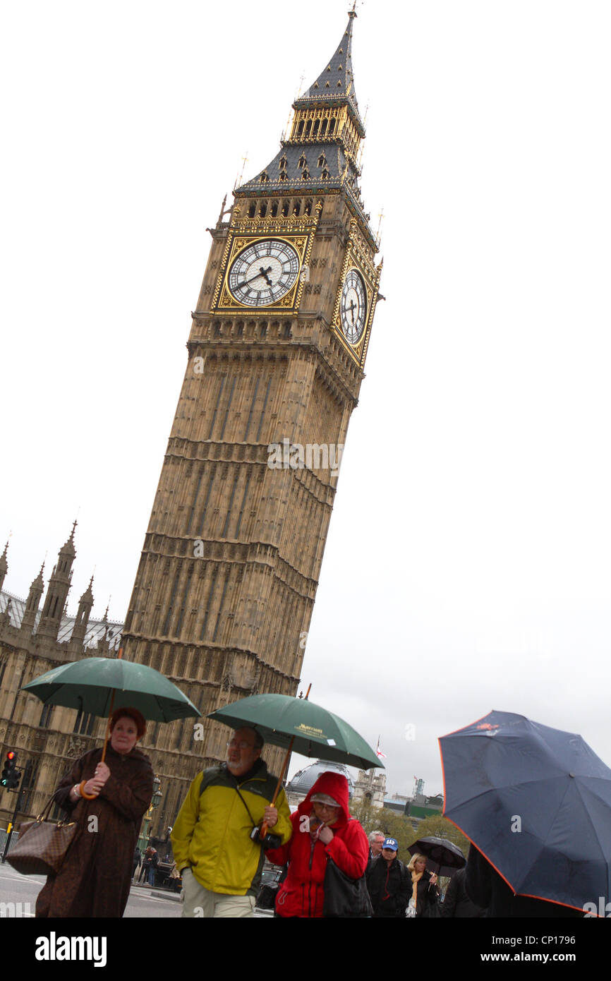 Persone con ombrelloni fino a piedi passato il Big Ben a Londra Foto Stock