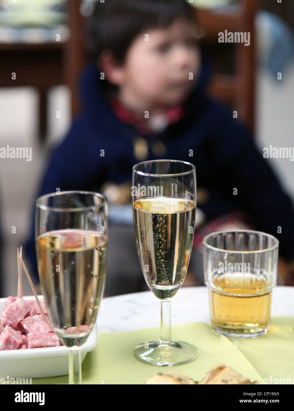 Si tratta di una foto di 3 bicchieri di alcol con un fuori fuoco boy in background. Vi è lo Champagne e sidro. Siamo in grado di vedere gli spuntini. Foto Stock
