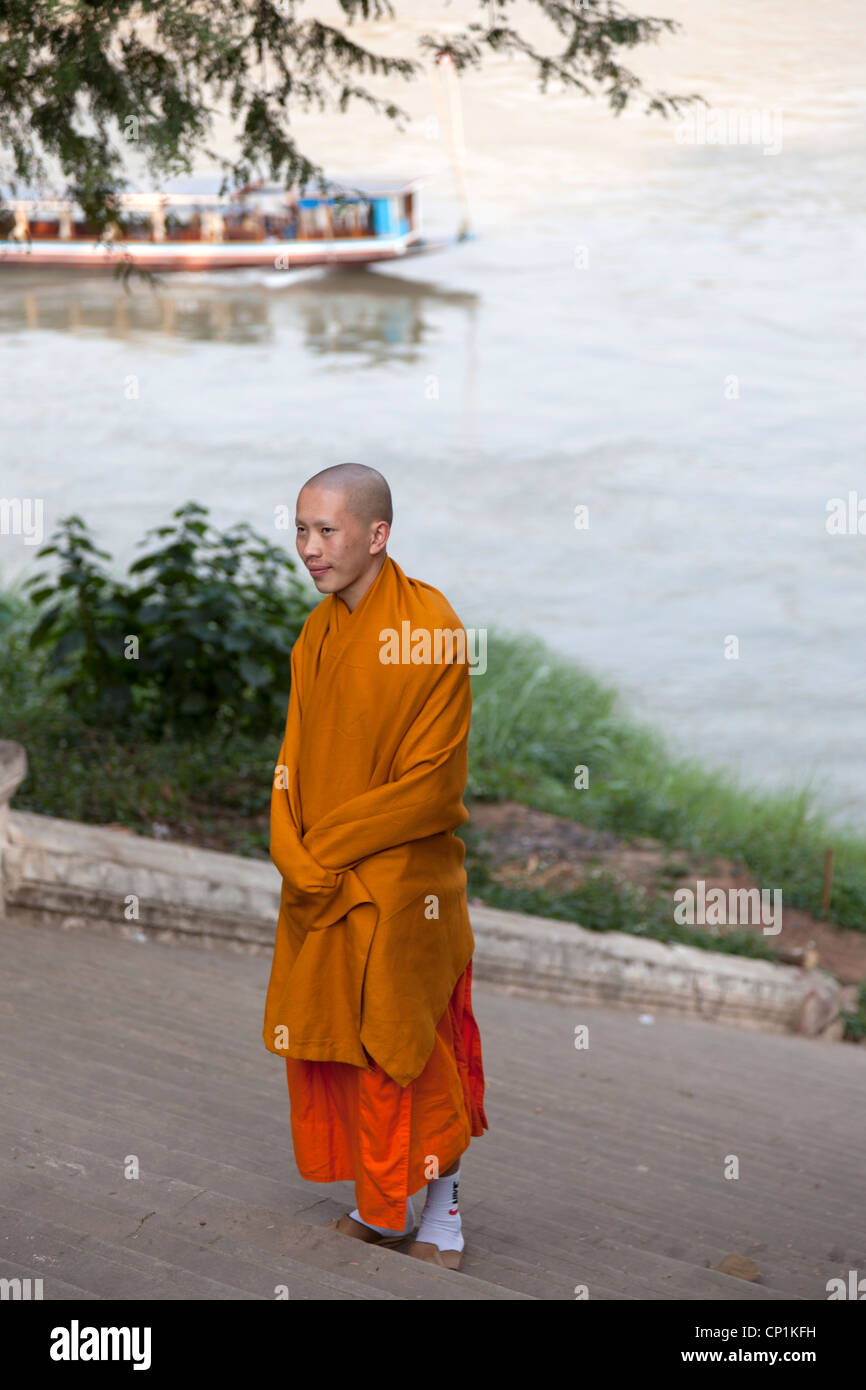 Nelle prime ore del mattino, un shivery monaco buddista su una banca del fiume Mekong (Laos). Moine frileux au petit matin (Laos). Foto Stock
