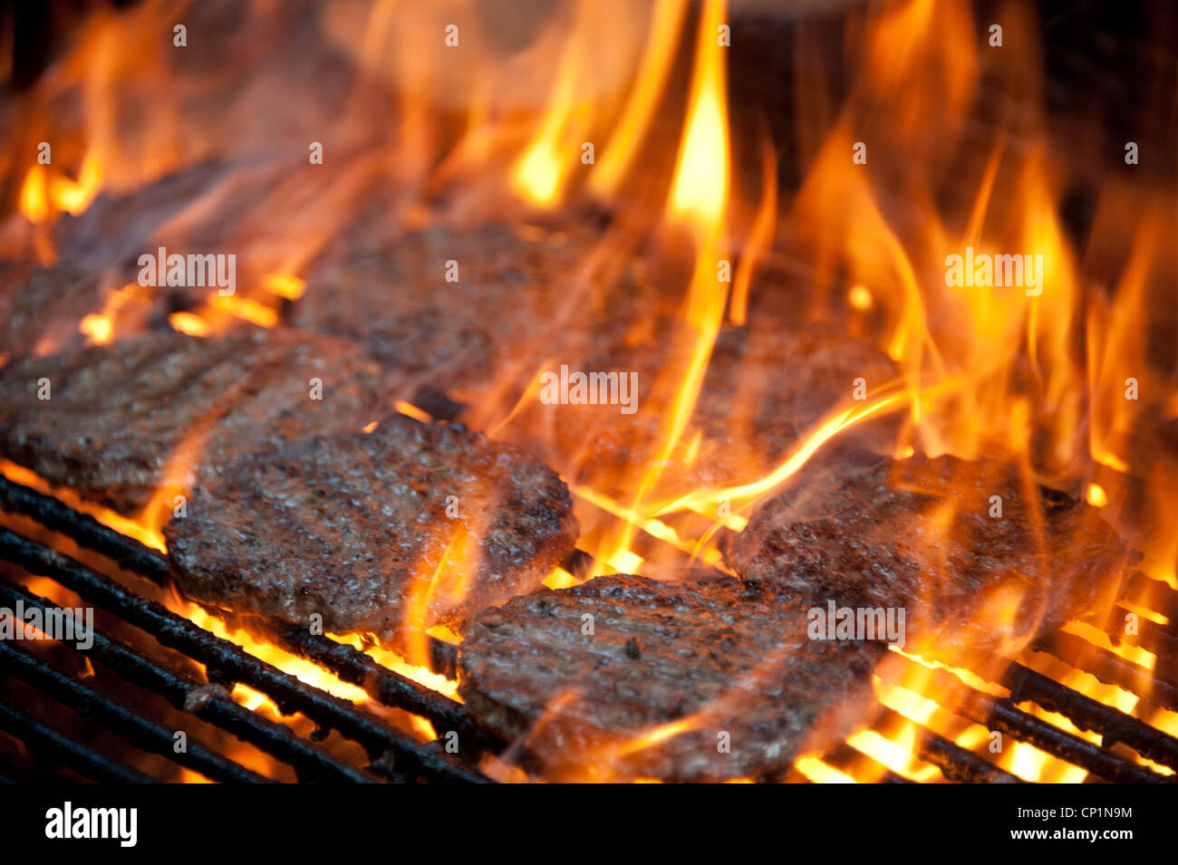 Gli hamburger sul grill avvolto in fiamme Foto Stock