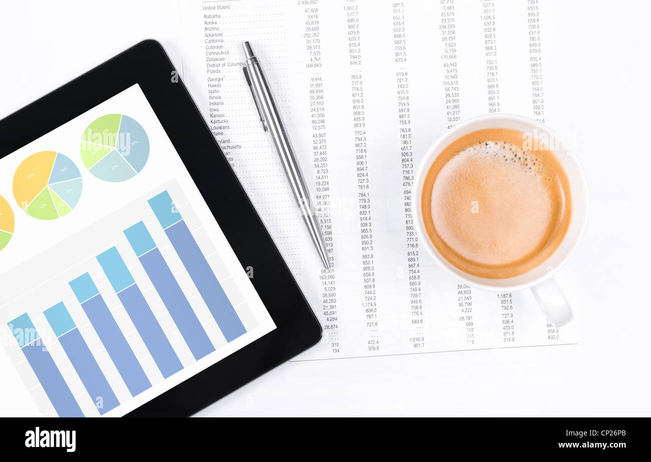 Ambiente di lavoro moderno con tavoletta digitale che mostra grafici e schema sullo schermo, caffè, penna e carta con i numeri. Foto Stock