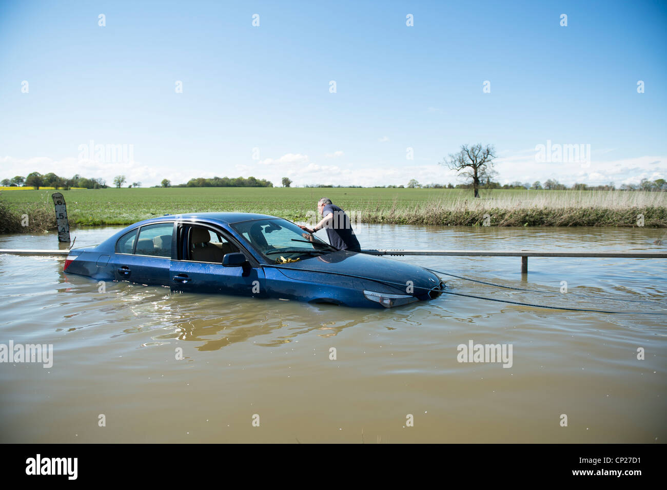 Una BMW auto è intrappolato in alluvioni in una Ford che è diventata troppo profondi a causa di piogge torrenziali. Un uomo cerca di attaccare una fune ad esso Foto Stock