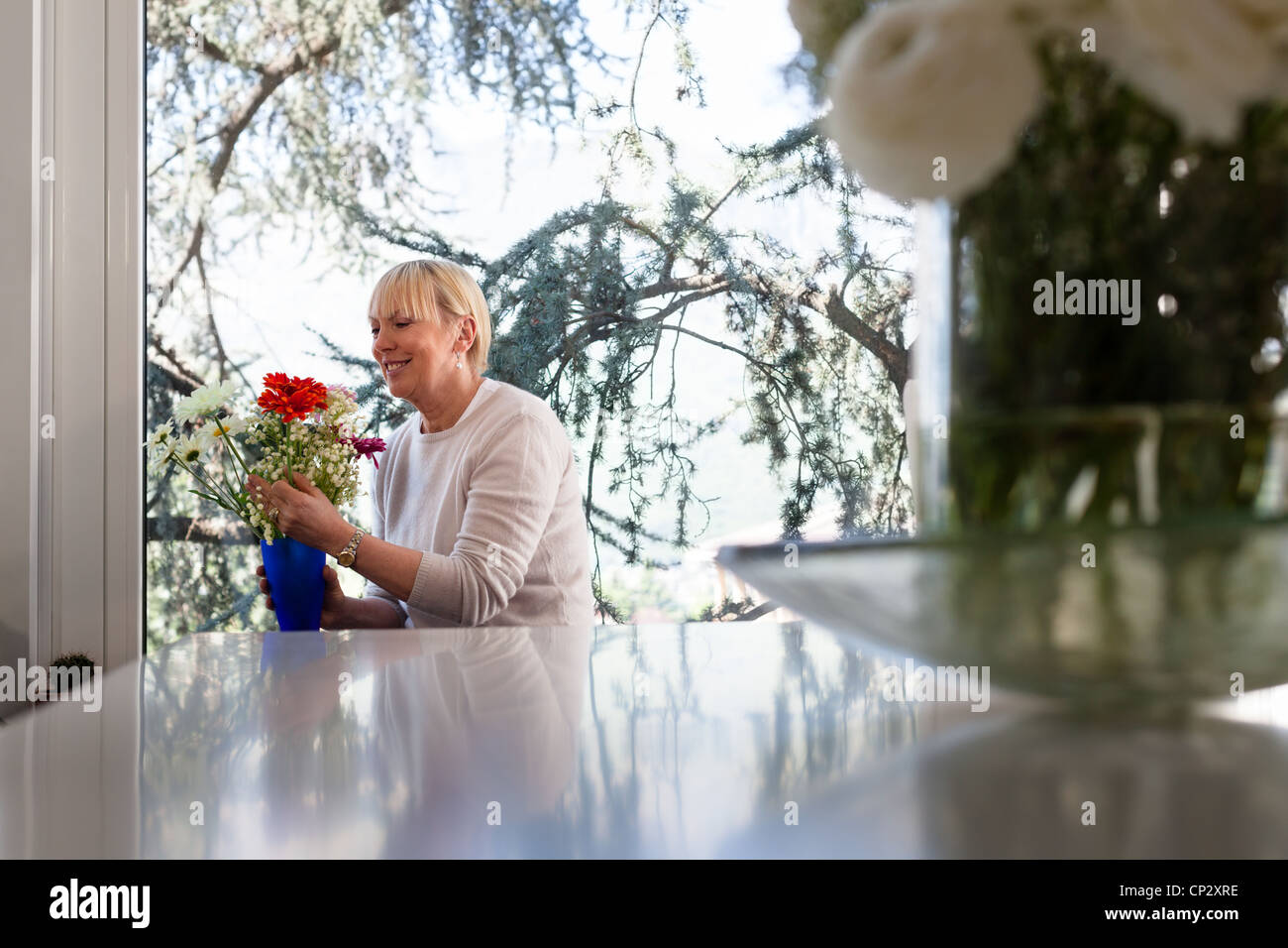 Senior donna caucasica con mazzo di fiori nel salotto di casa Foto Stock