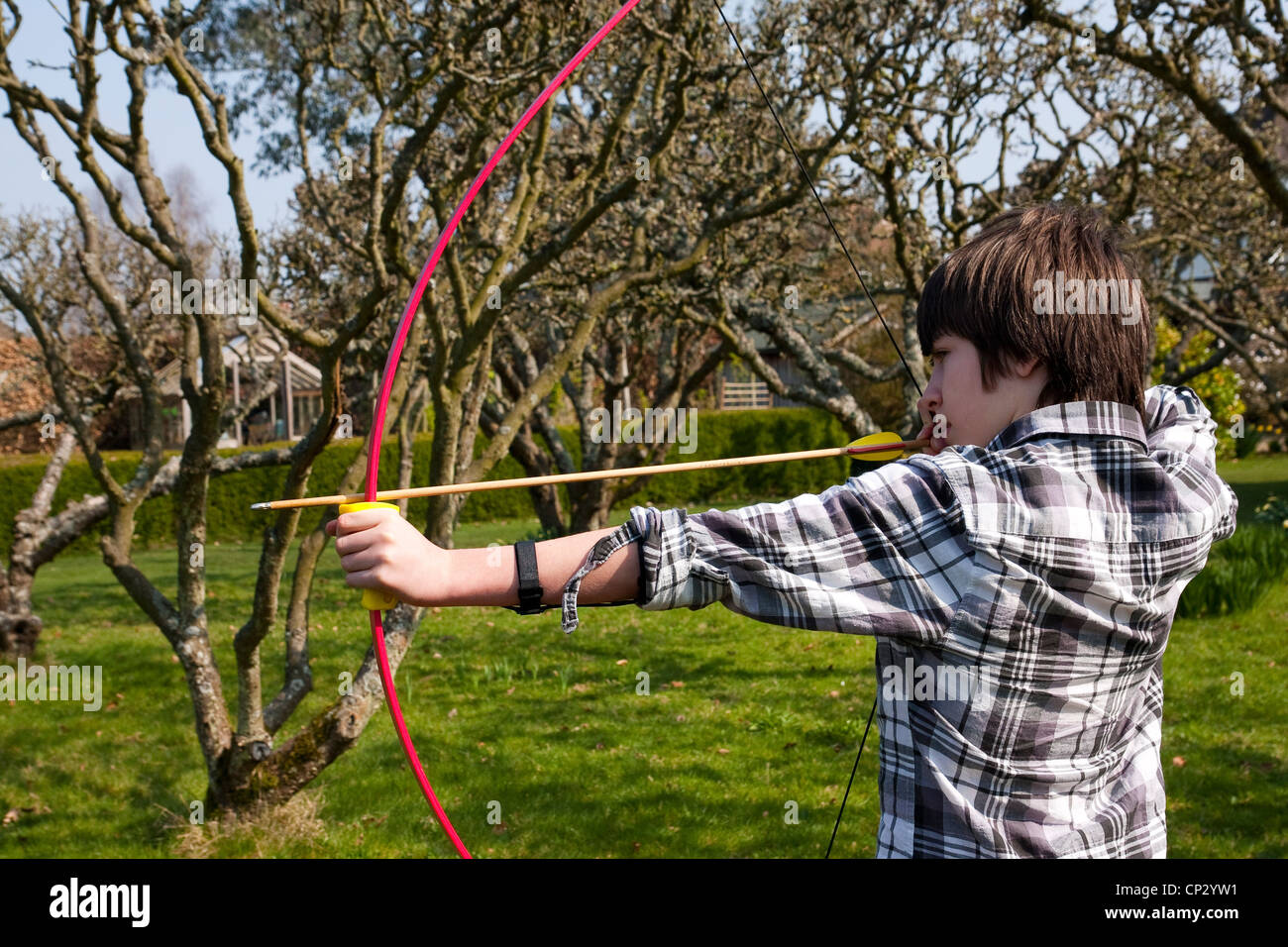 Ragazzo praticare il tiro con l'arco nel giardino Foto Stock