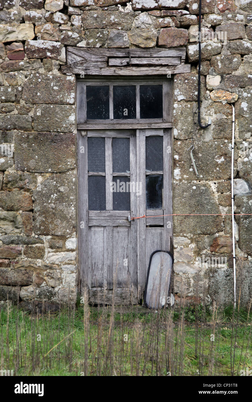 Avevo una porta di una vecchia casa di pietra in Normandia in Francia. La porta è rotta, la finestra come bene. È abbandonato. Foto Stock