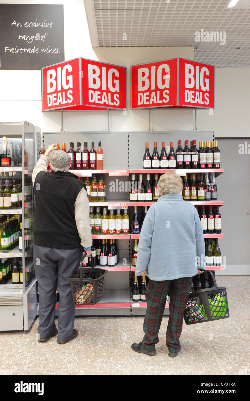 Il vecchio uomo e donna pensionati acquisti in un supermercato nel vino corsia. Foto Stock