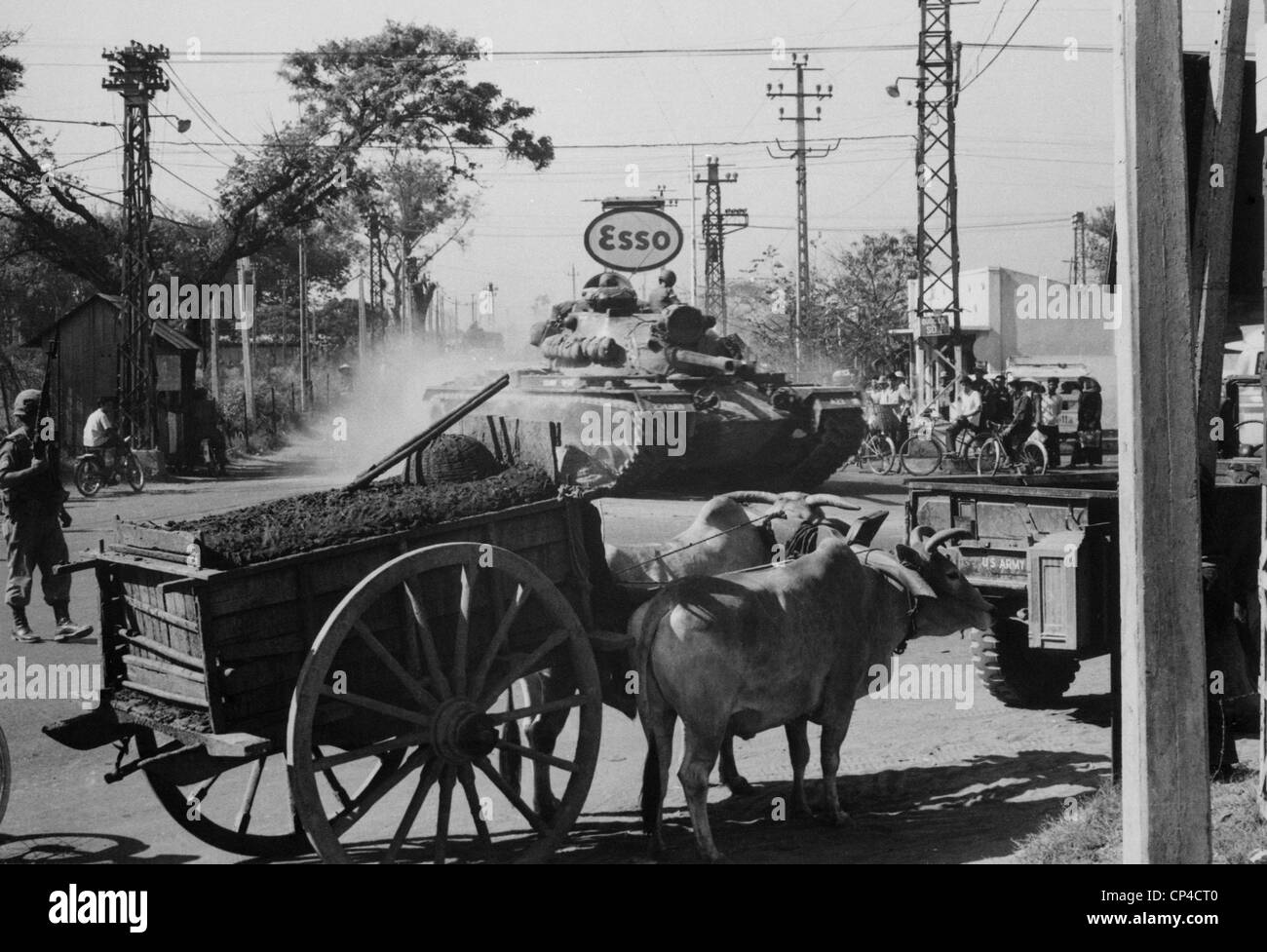 Guerra del Vietnam. Un esercito americano condivide serbatoio le strade di Saigon con ox carri durante il secondo anno di noi escalation della guerra. Foto Stock