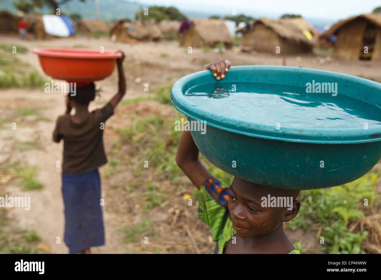 Una ragazza porta un contenitore pieno di acqua sul suo capo all'Miketo IDP camp, Katanga provincia, Repubblica Democratica del Congo Foto Stock