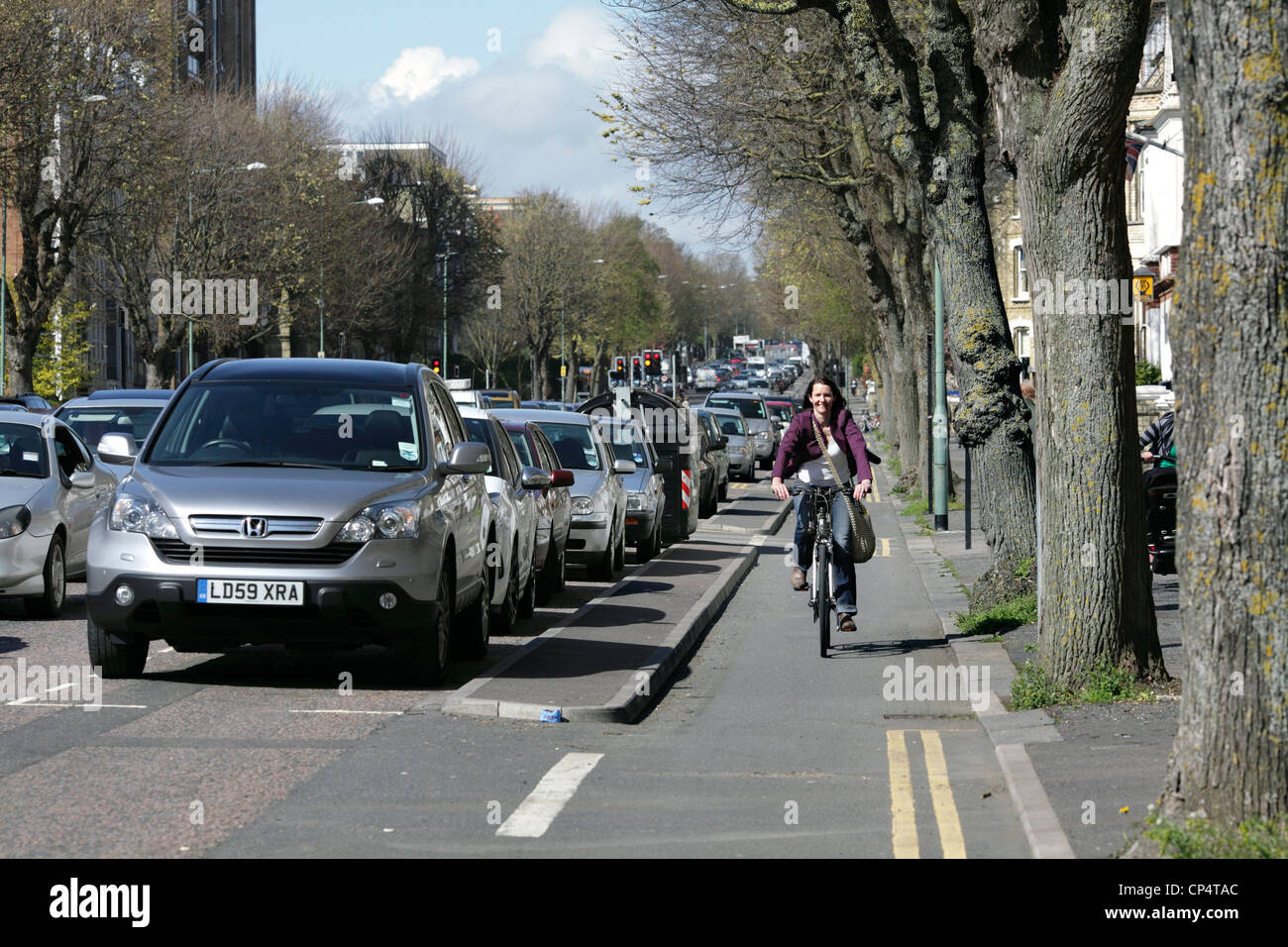 Ciclista a cavallo lungo una pista ciclabile separata dalla strada adiacente, il Drive, Hove. Foto Stock