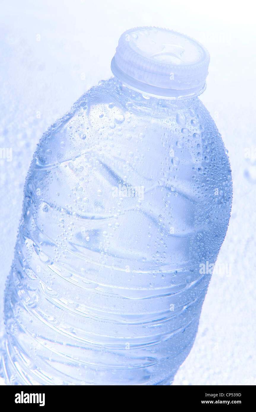 Primo piano di una bottiglia di acqua coperta con le goccioline d'acqua. Intenzionale toni freddi e la profondità di campo Foto Stock