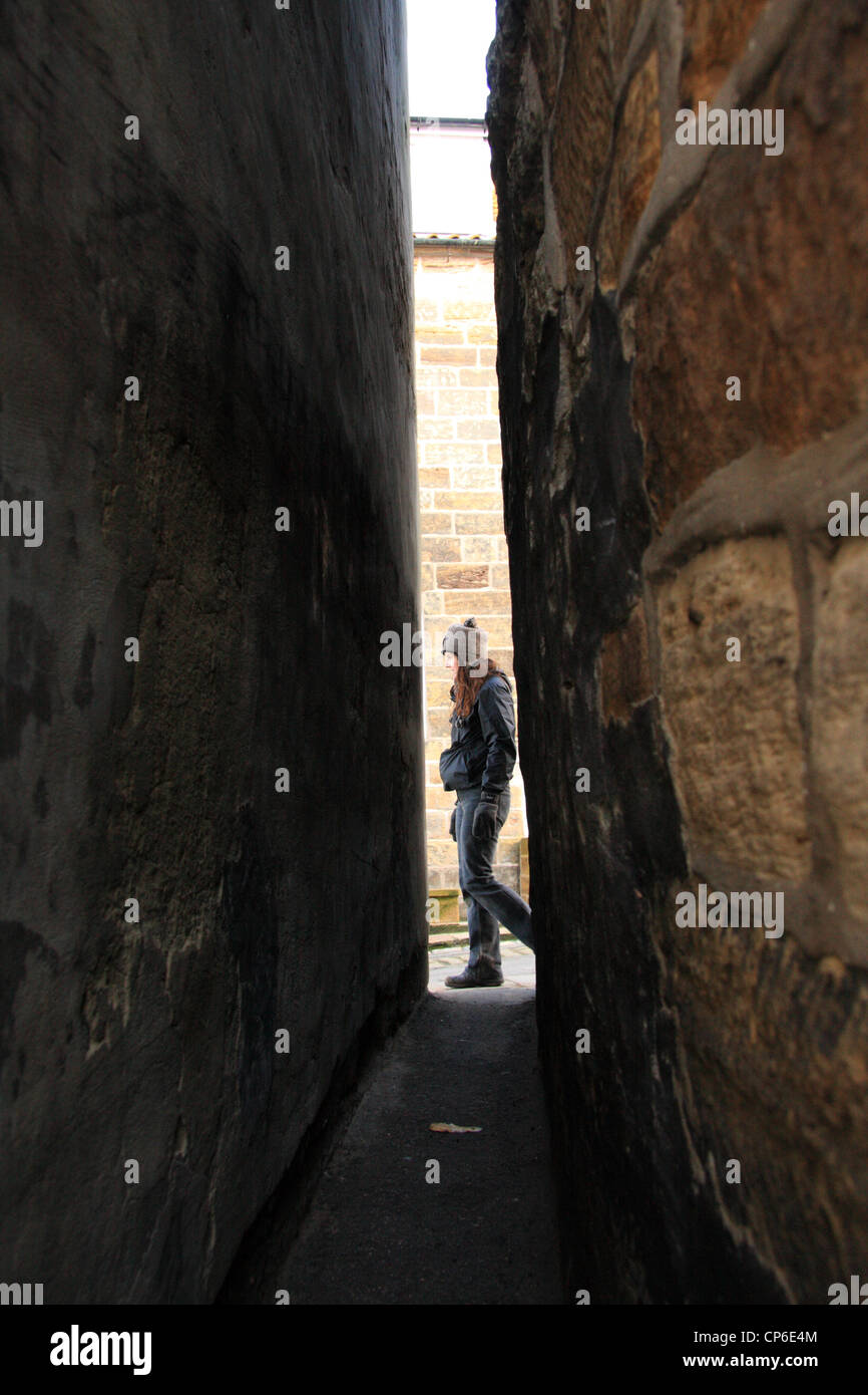 Donna waler passa il vicolo più stretto nel Regno Unito - chiamato cane Loup, Staithes, North Yorkshire, Inghilterra, Regno Unito Foto Stock
