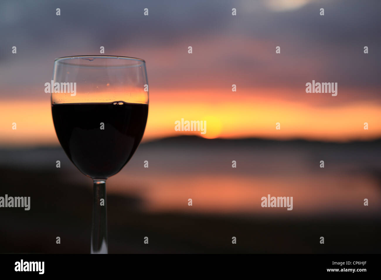 Bicchiere di vino rosso contro un tramonto mozzafiato Foto Stock
