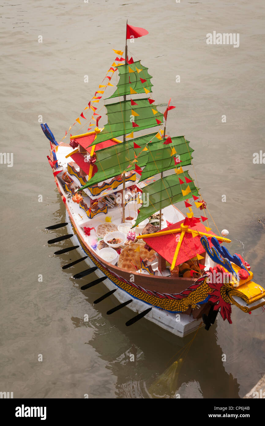Una replica in miniatura barca modello, caricato con i religiosi offerte per la dea del mare, su Thu Bon River, Hoi An, Vietnam Foto Stock