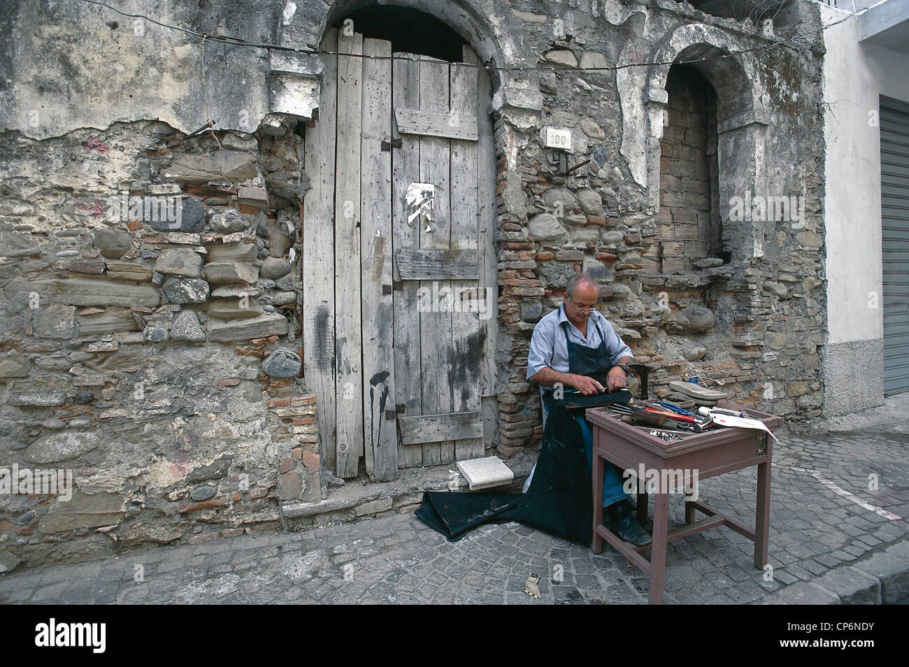 Calabria - Cirò Marina (KR), un artigiano al lavoro in un vicolo Foto Stock