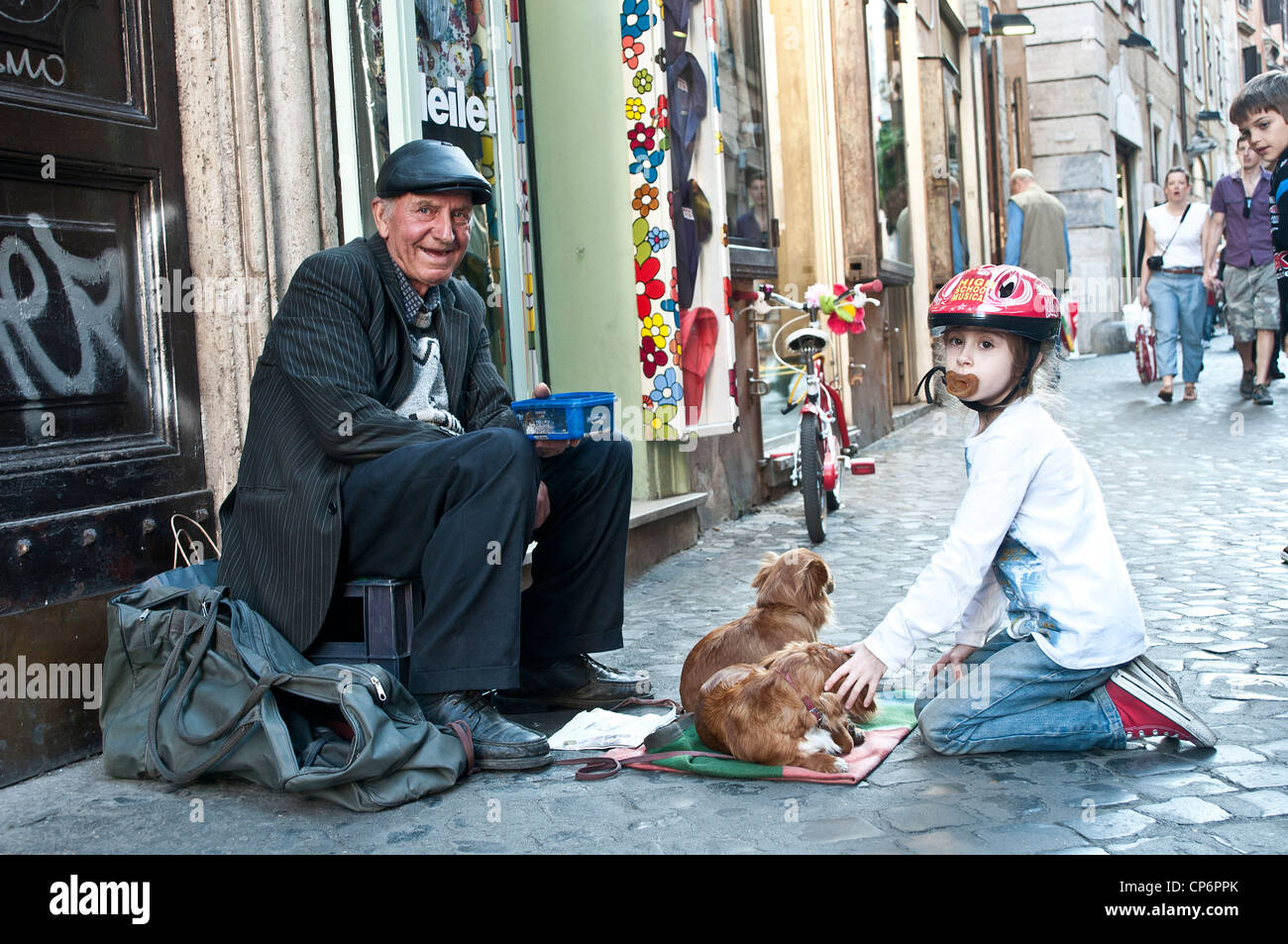 Piccola ragazza con succhietto e bicicletta fondling cani di un sorridente povera persona Foto Stock