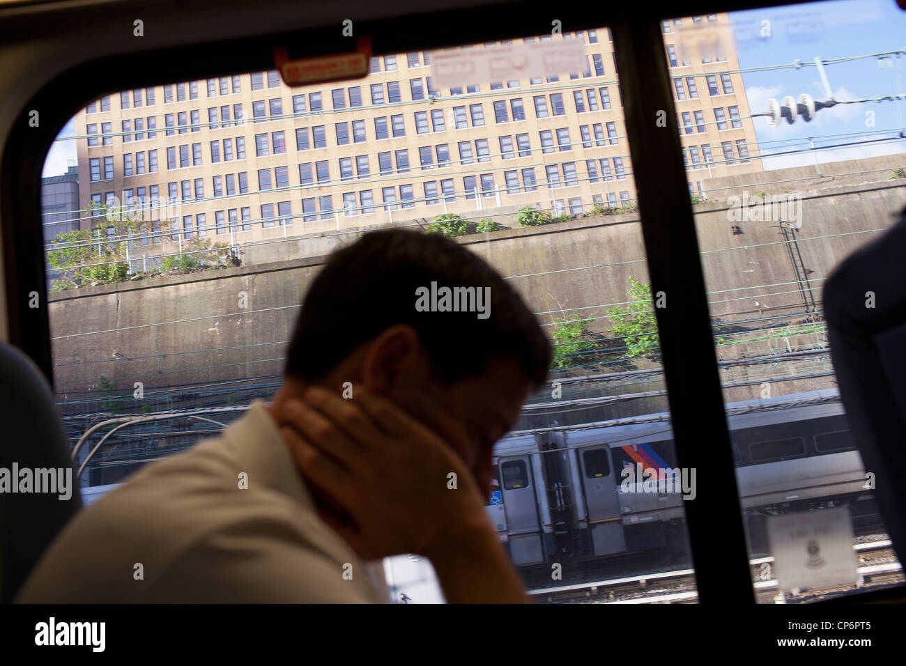 Un uomo legge dal suo computer mentre escono attraverso New York's Penn Station su Amtrak's Acela Express train per la stazione di Washington, DC. Foto Stock