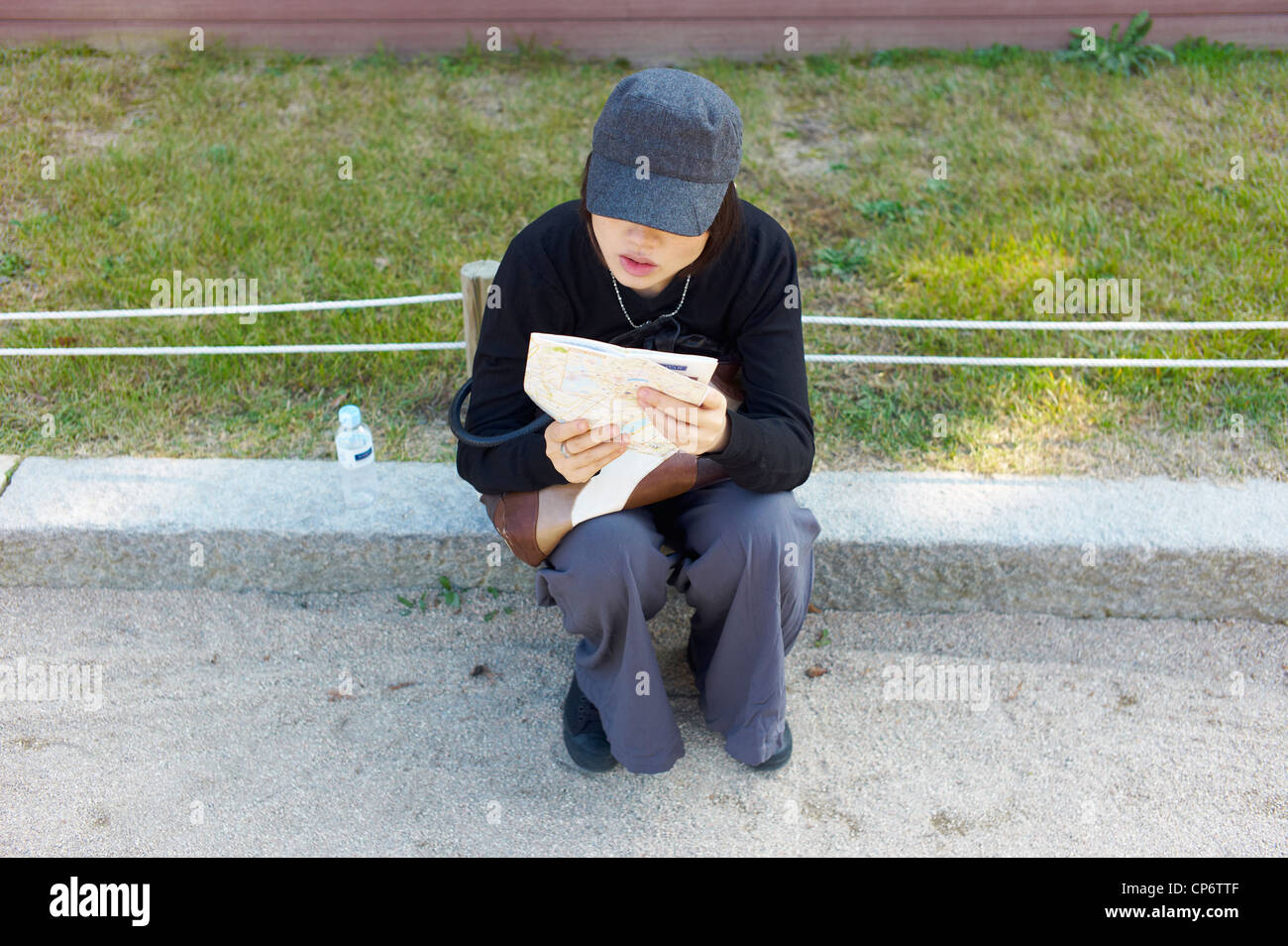 Una donna si siede per studiare la sua mappa Foto Stock