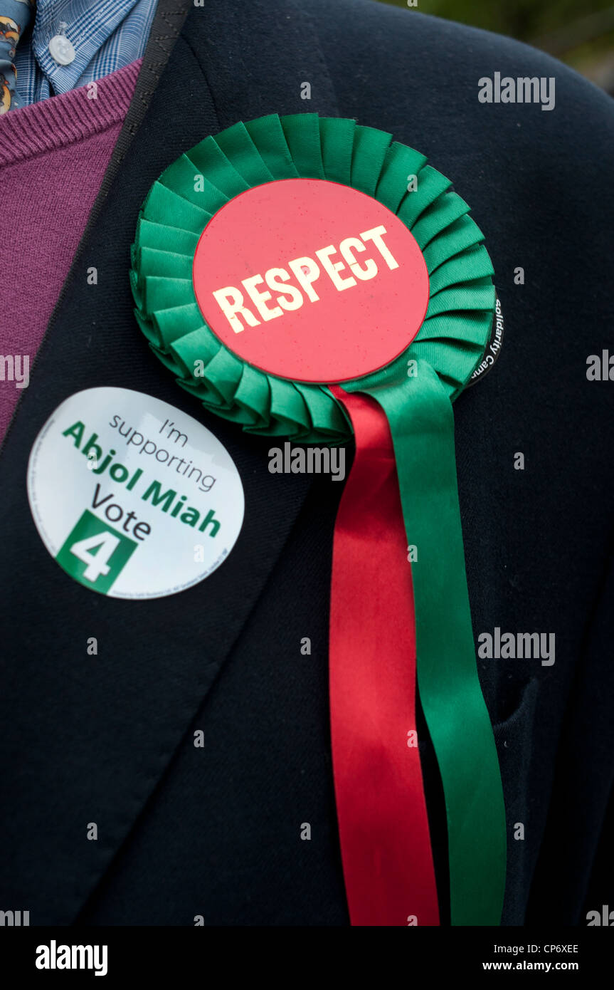 Maggio 3 2012 Londra elezione. Columbia Road centro di polling.uomo che indossa il rispetto delle parti rosette con il badge per Abjol Miah Foto Stock