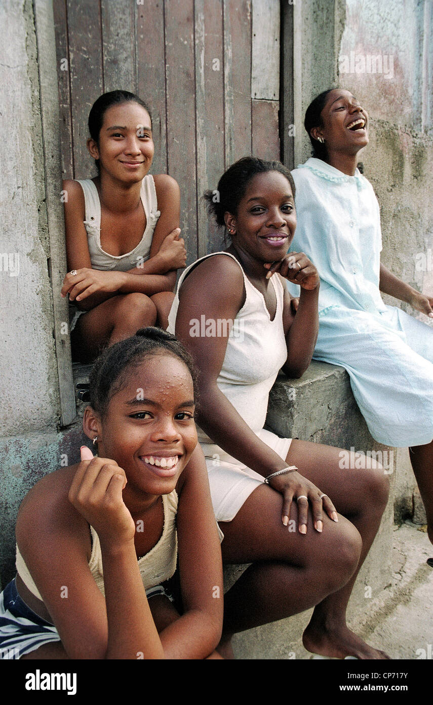 Sorridere le donne e le ragazze seduti insieme nella parte anteriore di una casa a Santiago de Cuba, Cuba Foto Stock