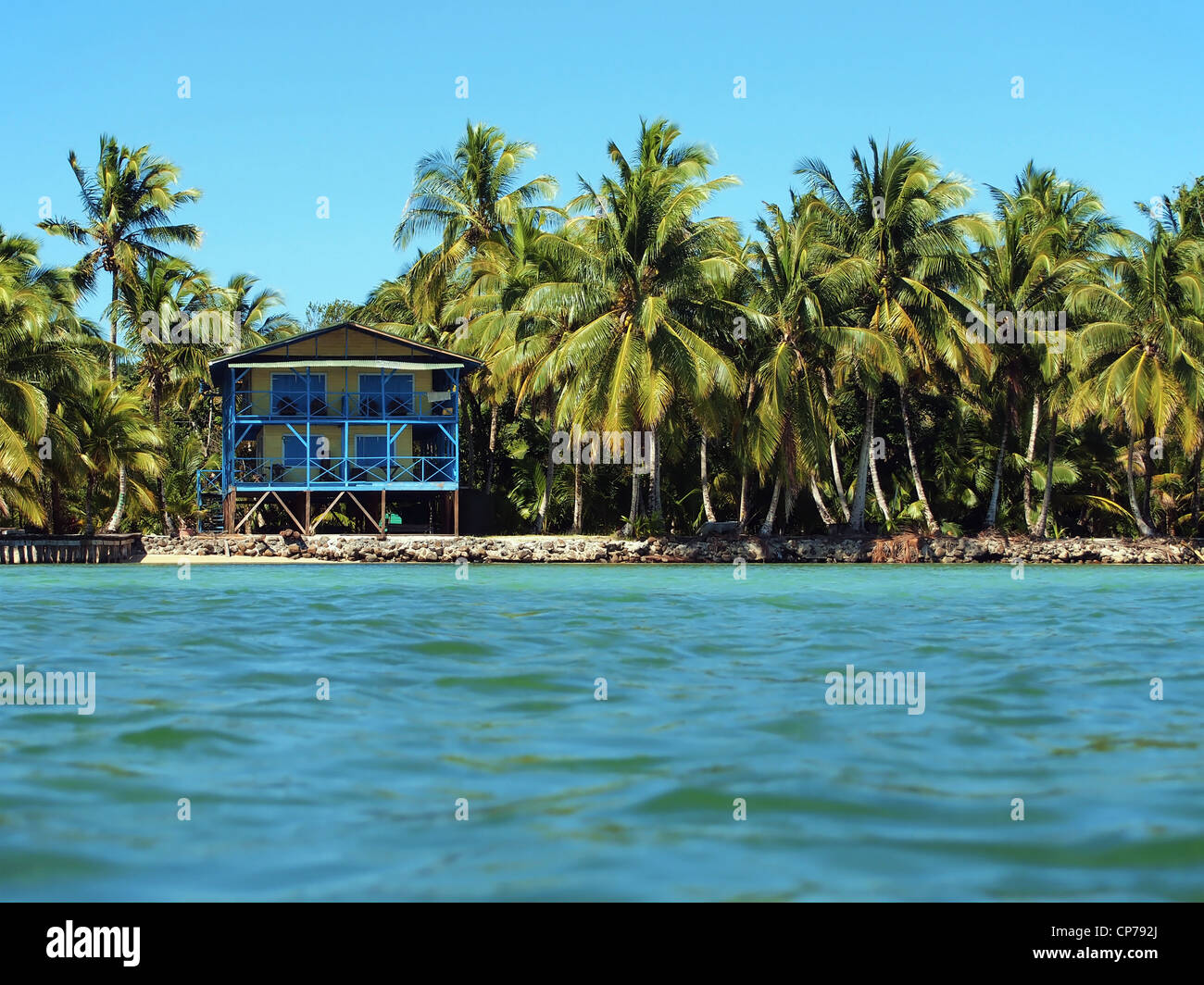 Sul fronte oceano casa tropicale su un isola dei Caraibi con lussureggianti alberi di noce di cocco, Panama America Centrale Foto Stock