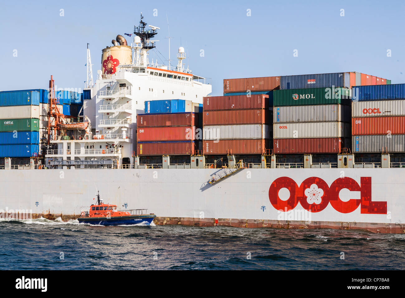 OOCL nave portacontainer " Amicizia' lasciando porto di Fremantle, Western Australia, assistito dal pilota di barca 'Clairmont'. Foto Stock